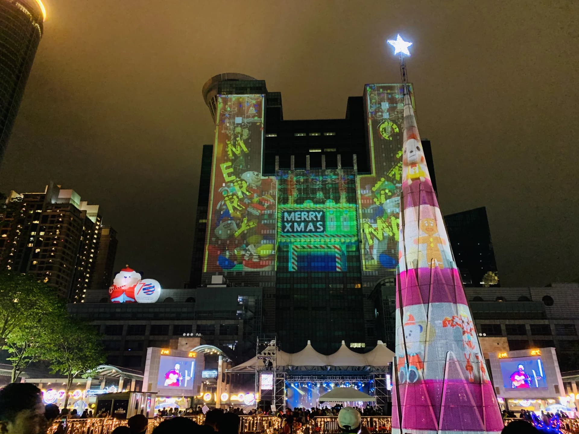 新北歡樂耶誕城夜間燈光投影映照新北市政府大樓與耶誕樹